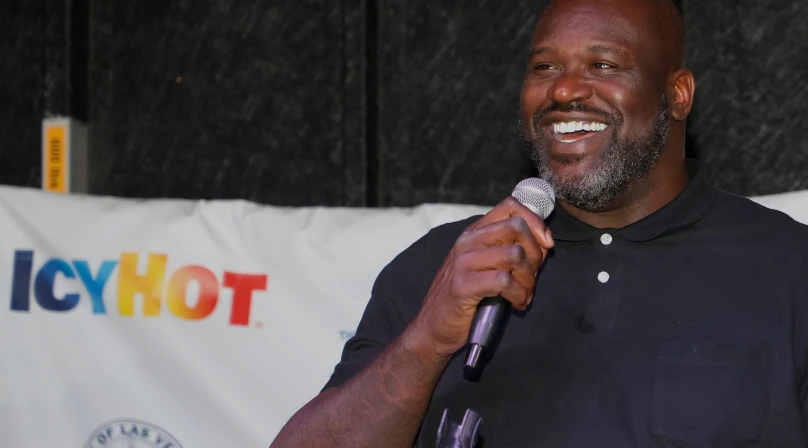 Shaquille O'Neil speaking at the inauguration of one of the Las Vegas Comebaq Court. He's holding a microphone on his right hand as he smiles. The Icy Hot logo can be seen in the background.